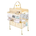 Foldable baby changing table with adjustable height, lockable wheels, fabric drawers, side basket, and hanging rod in light beige.